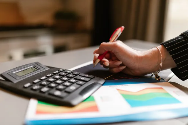 A business professional uses a calculator and documents during a workspace task. B2B lead marketplace fees: how to read a UK quote