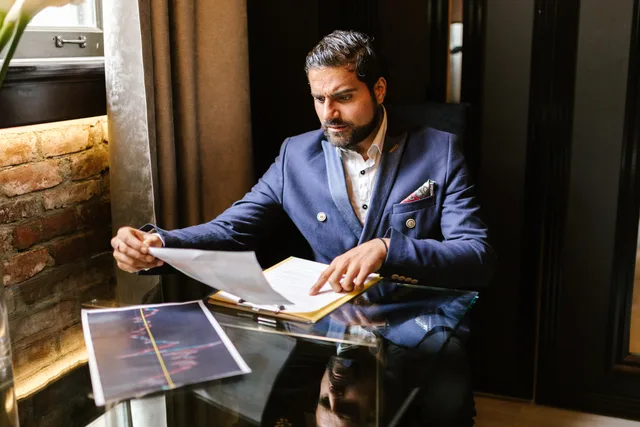 Businessman in blue blazer reviewing financial documents at a glass table. UK lead generation companies for accountants: what to ask before buying