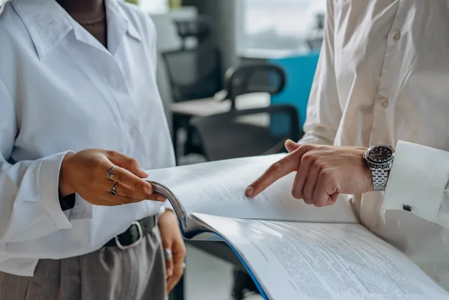Two business professionals discussing and reviewing documents in a modern office setting. Testing a lead network advert for identity, impression and substantiation