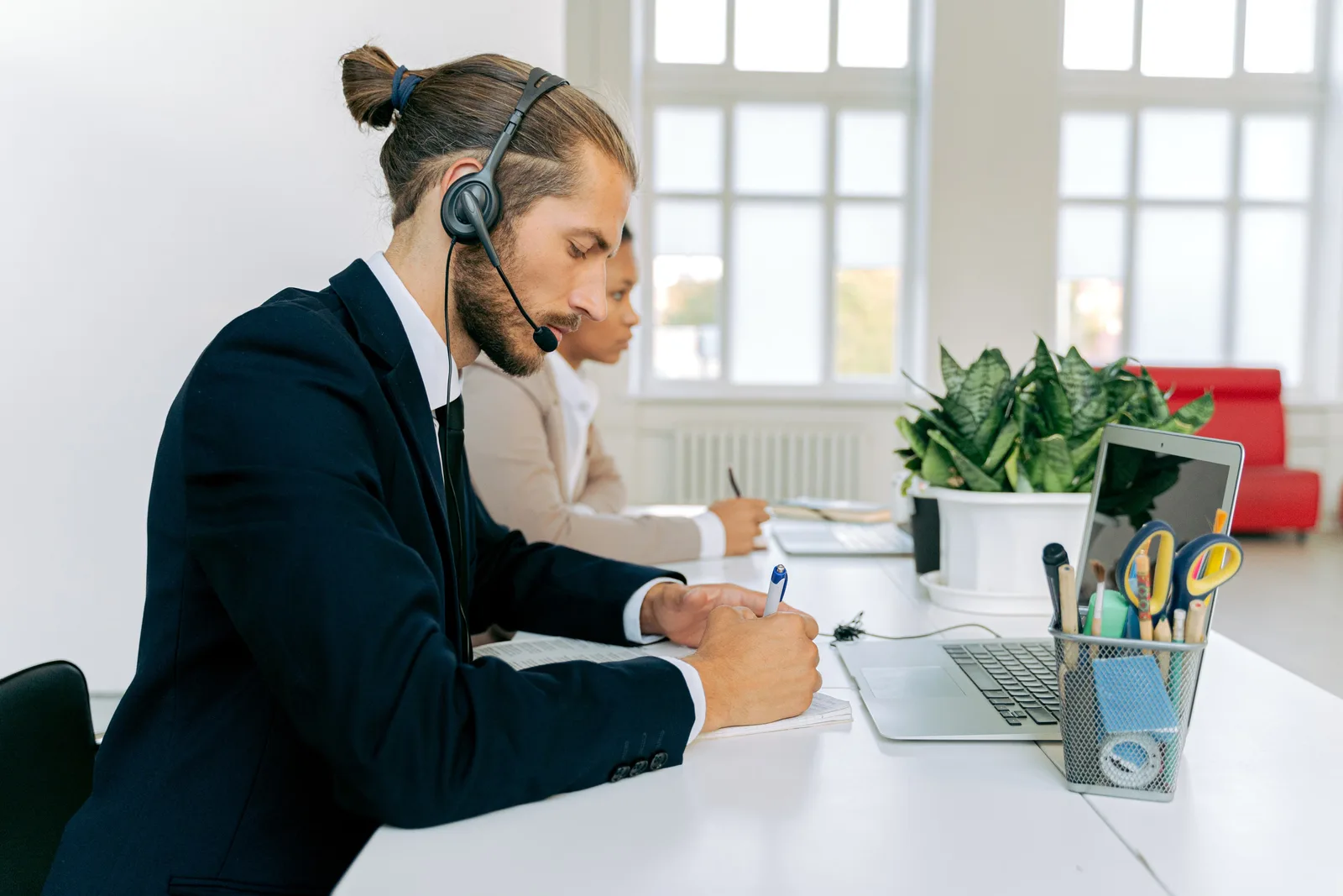 Customer service representative with headset working at office desk. Professional workspace environment.