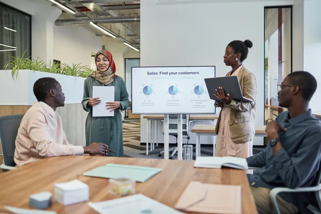 A diverse team discusses business strategy during an indoor presentation. Lead generation networks: choosing a channel strategy that fits