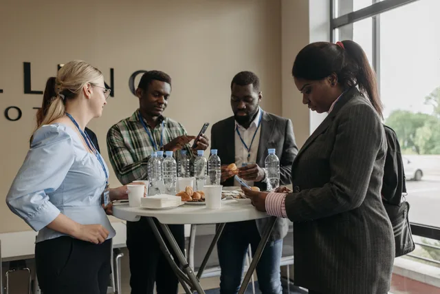 A group of diverse professionals networking and discussing business during a conference break indoors. Defining a lead network audience with requesters and buyers kept apart