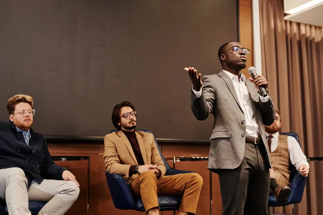 A diverse group of professionals engaged in a business panel discussion with a speaker presenting. How to vet the tools behind lead generation networks