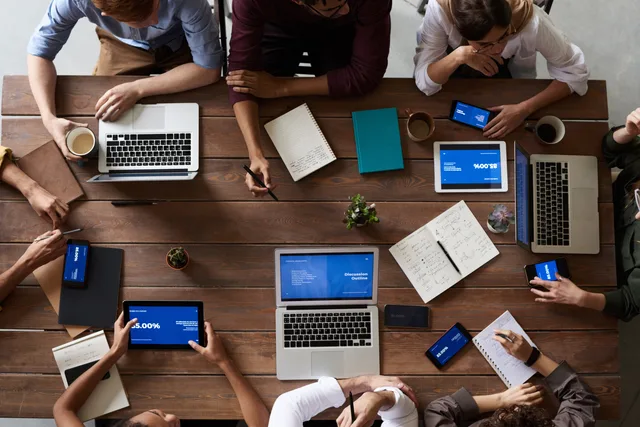 Overhead view of a diverse team in a business meeting using laptops and tablets. UK regulations for a lead network, with the DUAA dates entered twice